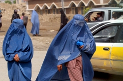 Image: Two Afghan burqa-clad women walk along a street in Kabul on May 6